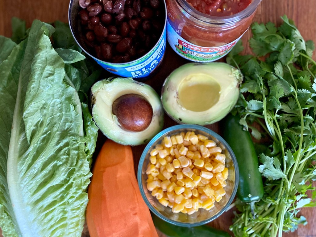 Ingredients for a basic vegan taco salad:
Avocado, black beans, cilantro, corn, jalapeños, lettuce, and sweet potato